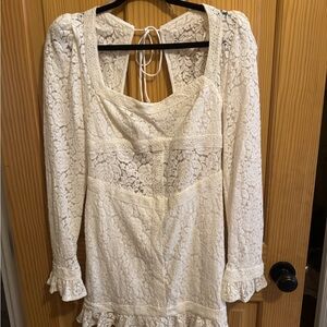 White lace dress with long sleeves and a ruffled hem